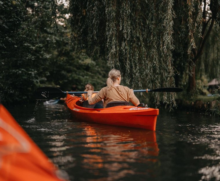 Frau paddelt im roten Boot im Fluss