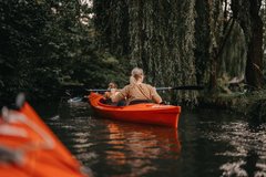 Frau paddelt im roten Boot im Fluss