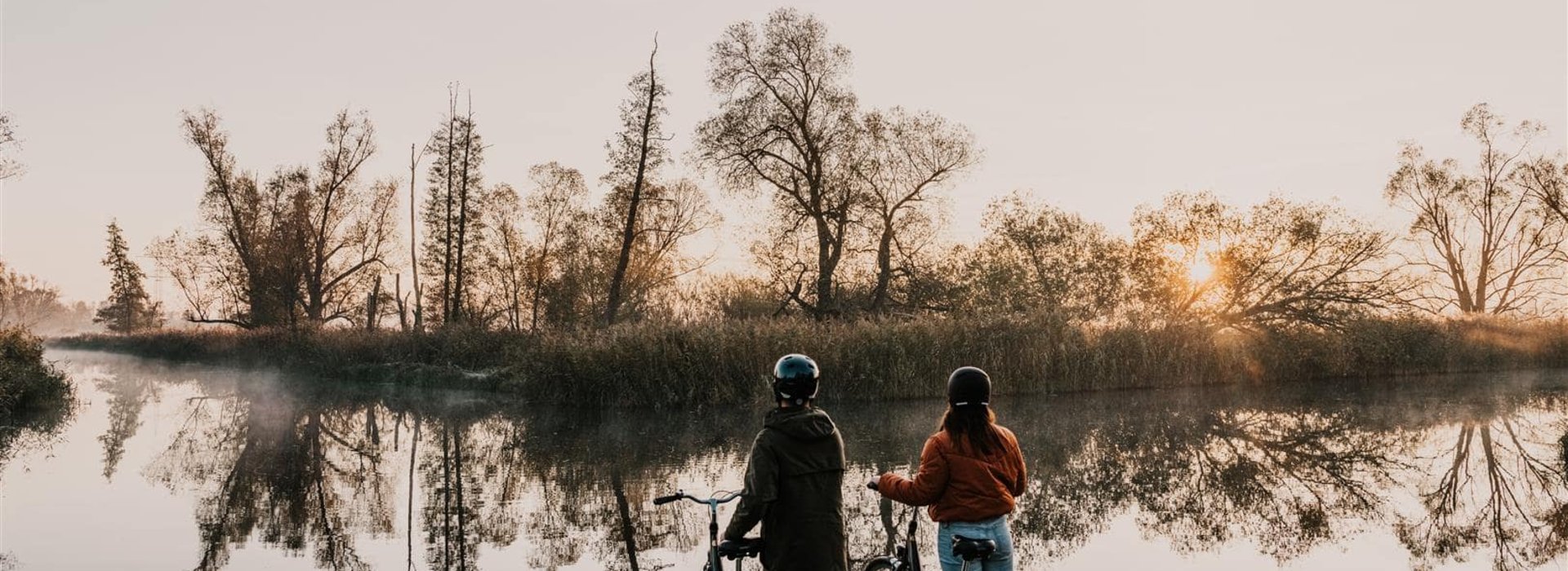 2 Radfahrer im Herbst vor Fluß im Spreewald bei Lehde
