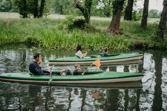 Family paddles 2 green boats in Spreewald forest