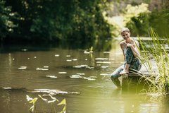 Woman sits after yoga in sportswear on the river in Spreewald and relaxes