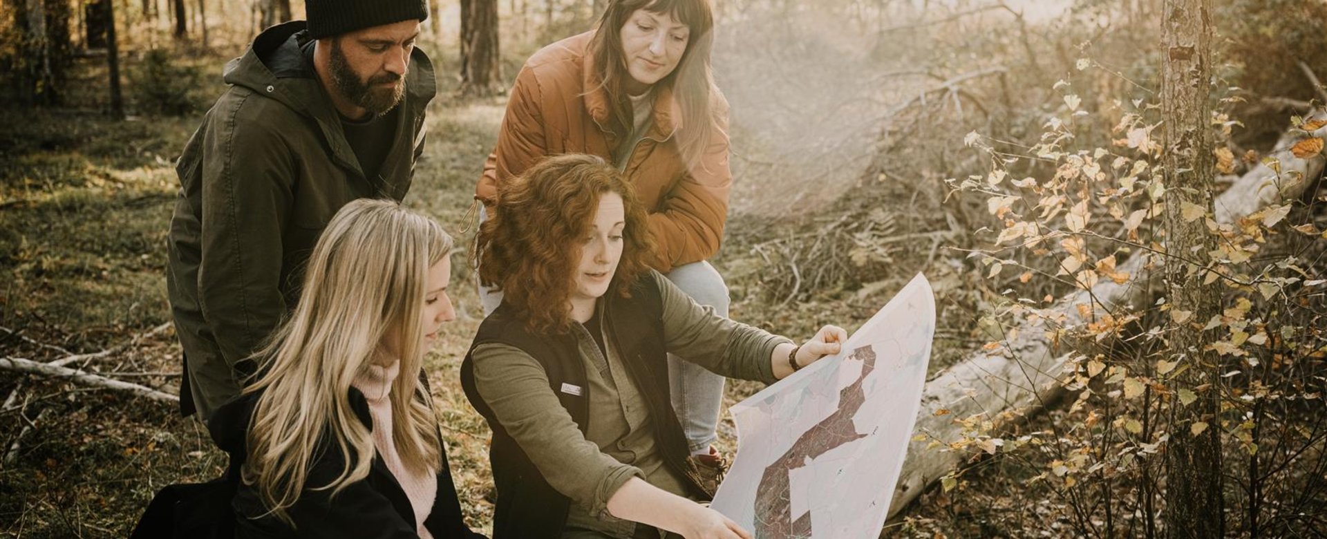 Gruppe sitzt vor Karte im Wald und orientiert sich
