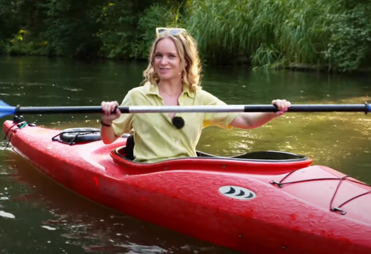Screenshot von englischem Video über den Spreewald Frau paddelt in rotem Boot in Fließen