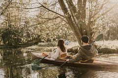 Woman and man in boat paddling through Spreewald river in autumn mood