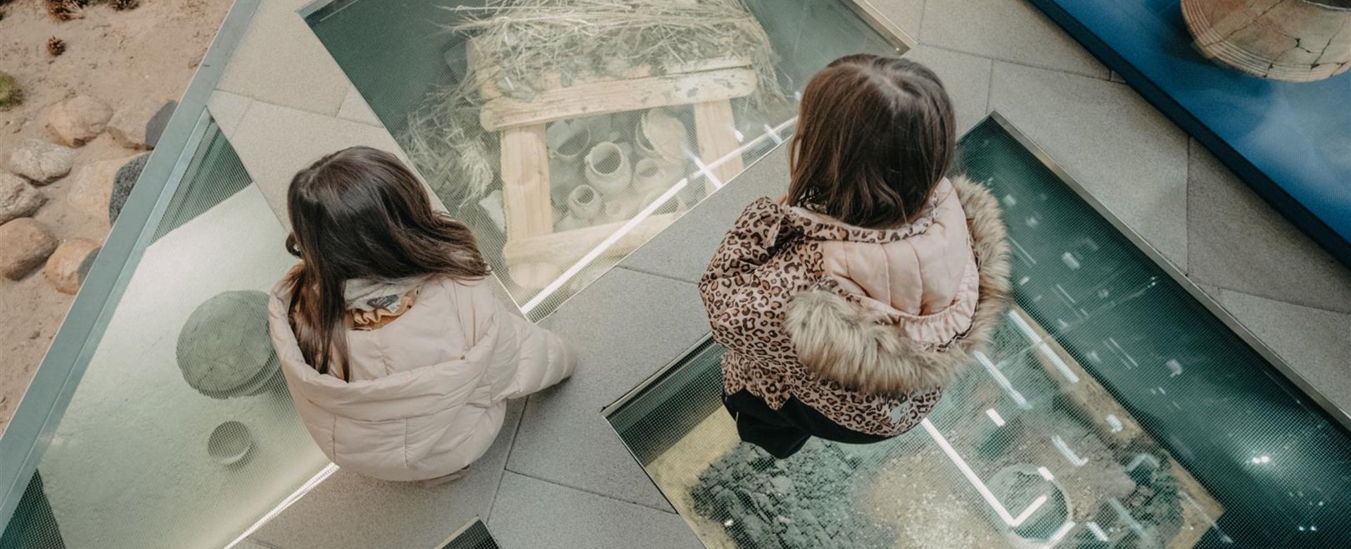 Museum Kinder über Glas mit Ausstellungsstücken darunter
