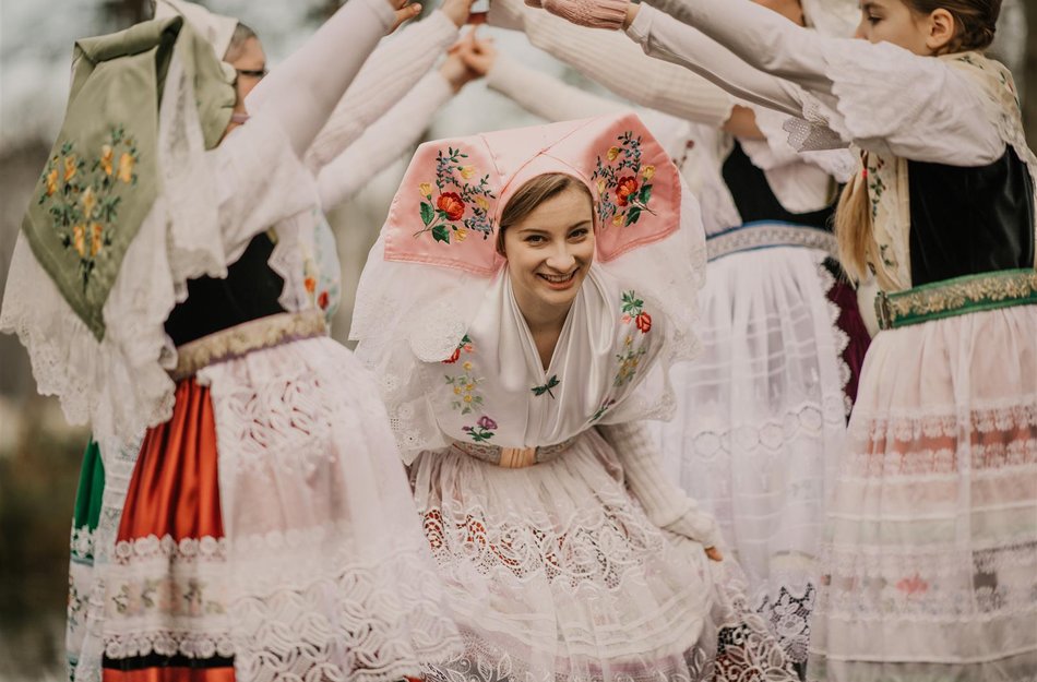 Trachtenverein Raddusch Mädchen tanzt durch Gasse die mit Armen von anderen traditionell angezogenen Trachtenmädchen gebildet wird