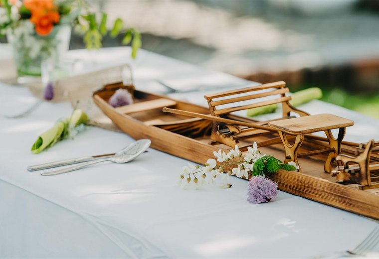 dekorierter Mittagessen Tisch mit kleinem Holzkahn als Deko und Blumen